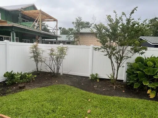 A white vinyl fence behind a garden bed after cleaning